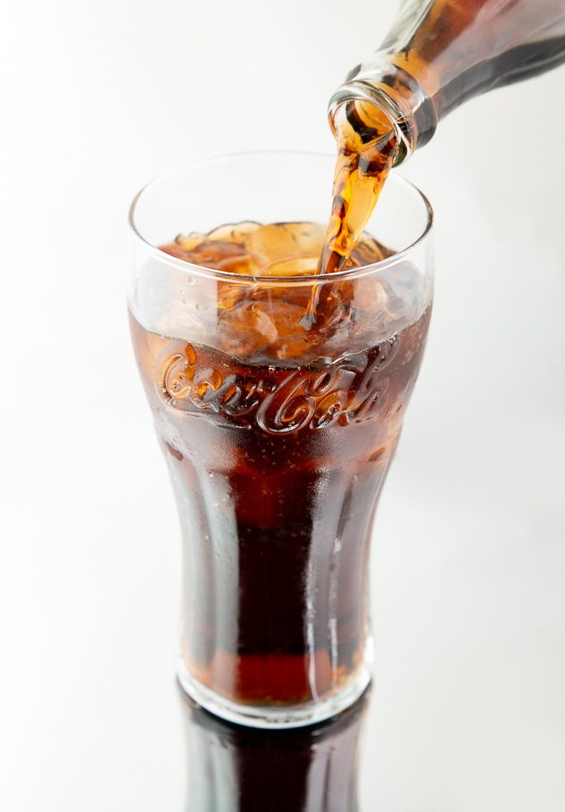 Pack shot of coca-cola being poured into a glass